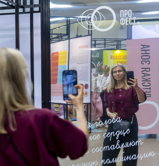 Женщина фотографирует свое отражение в зеркале